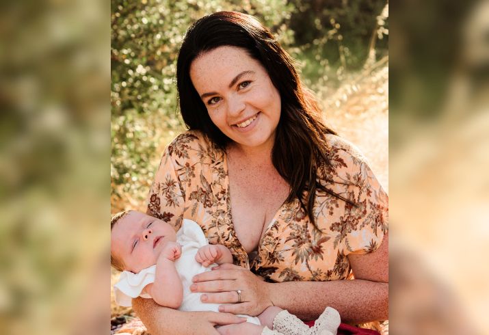 Amy O' Meagher sits in a garden setting holding a baby in her arms